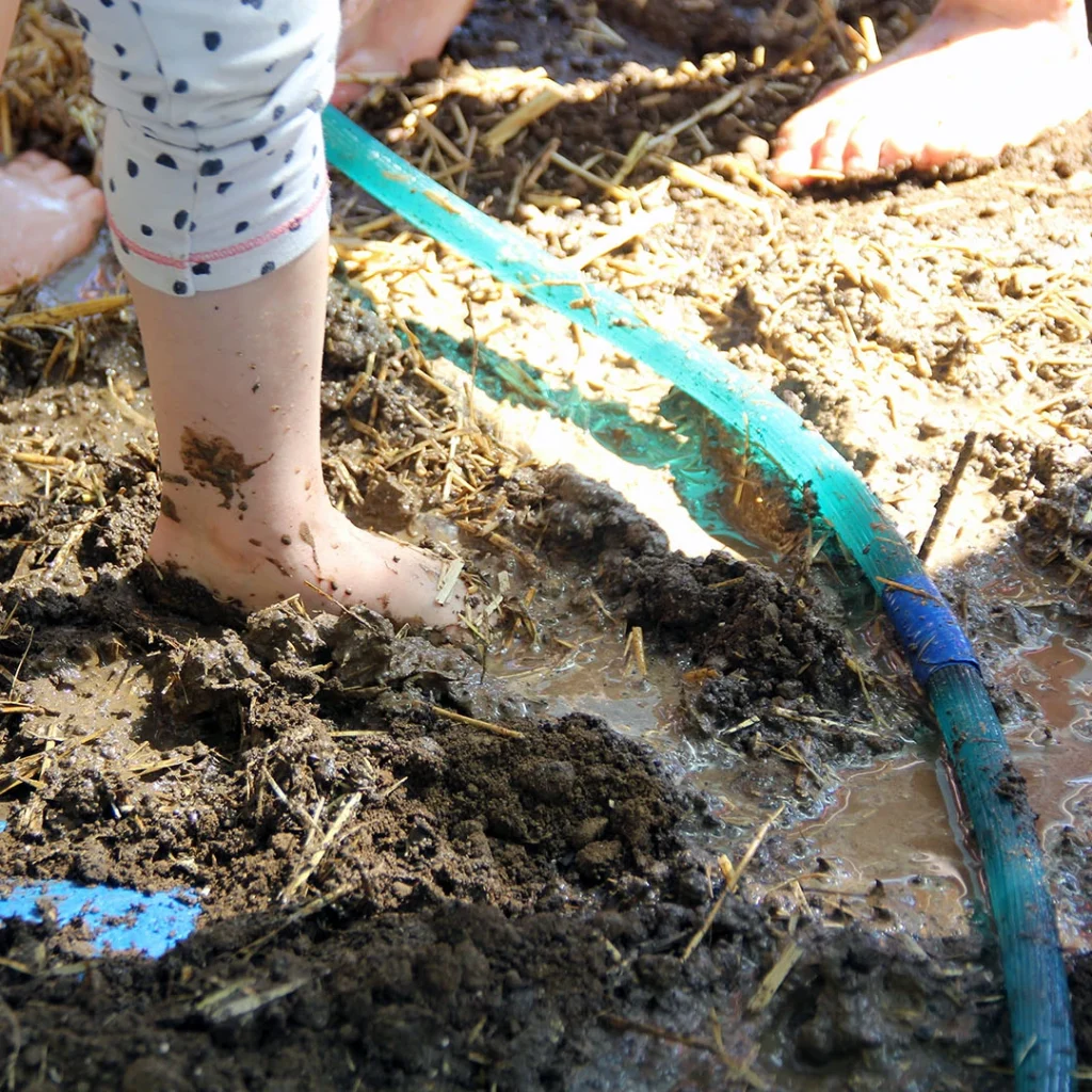Kinderfüsse stehen im Stroh-Lehm Gemisch