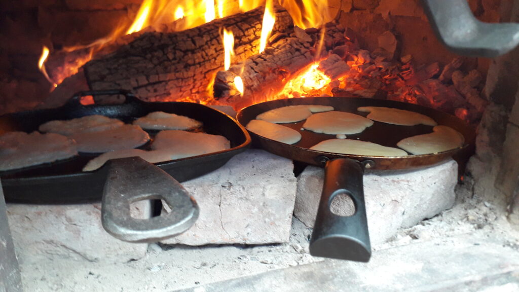 Pfannekuchen werden im brennenden Erdofen gebacken