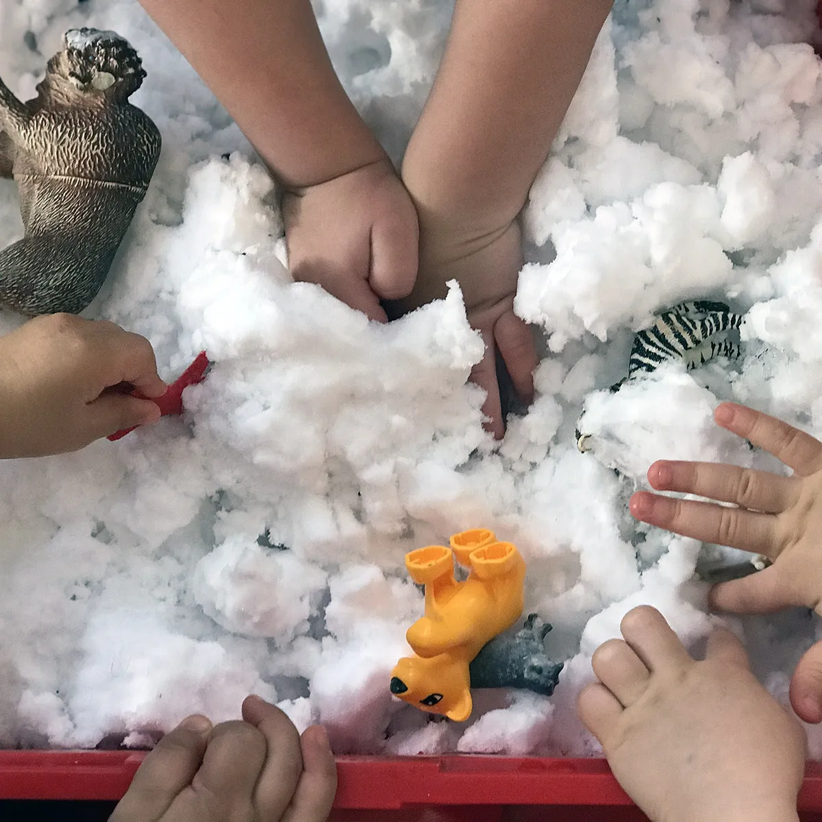 Kinderhände spielen mit Plastiktieren und Schnee