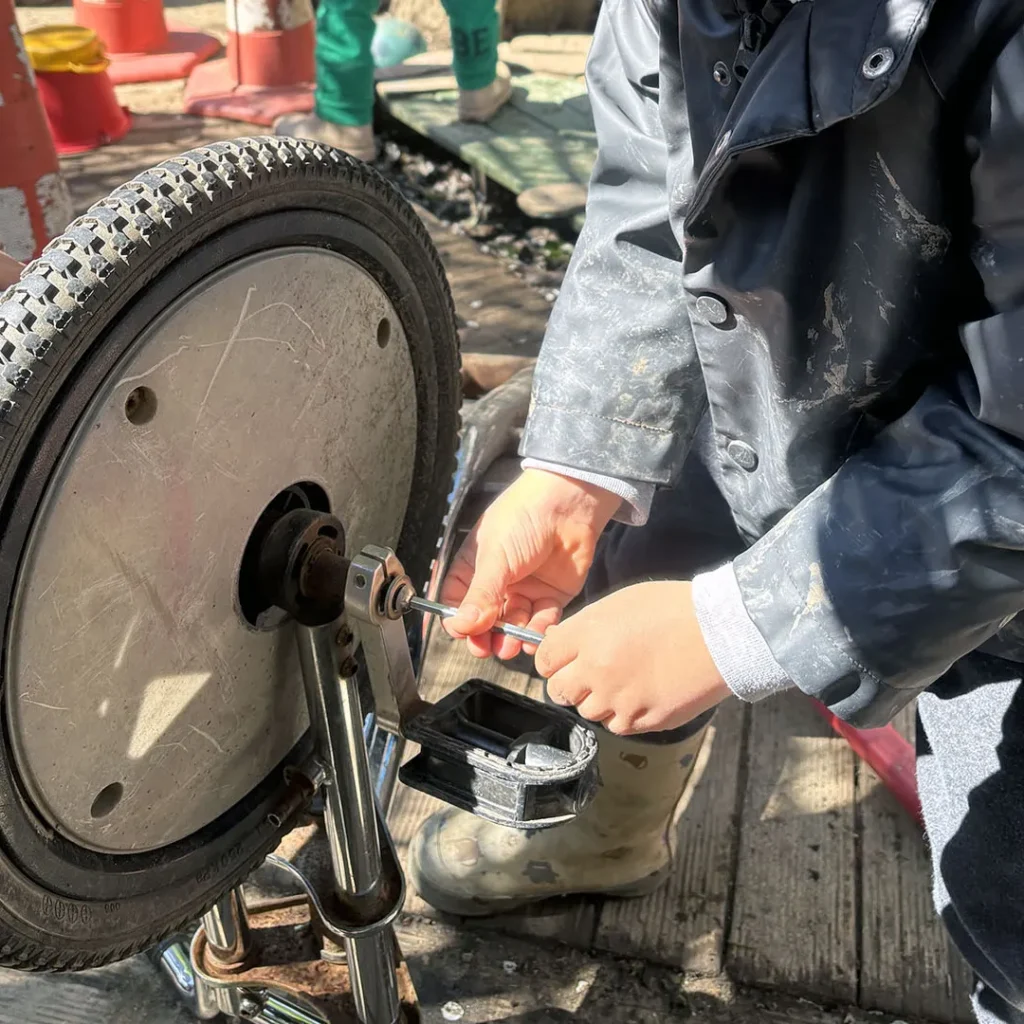 Ein Kind benutzt einen Schraubenzieher um ein Fahrrad zu reparieren