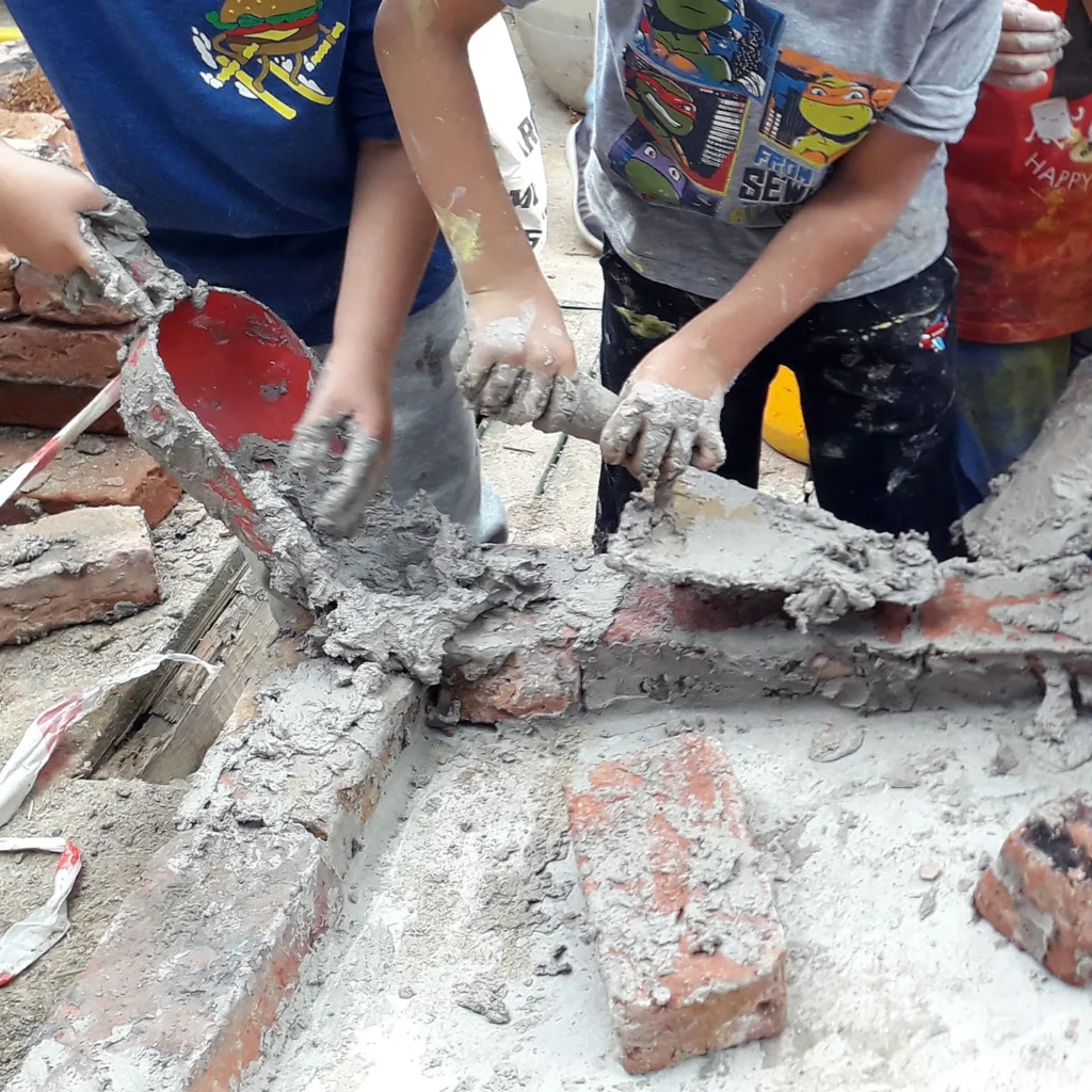 Die Kinder helfen beim mauern mit Backsteinen und Schamott