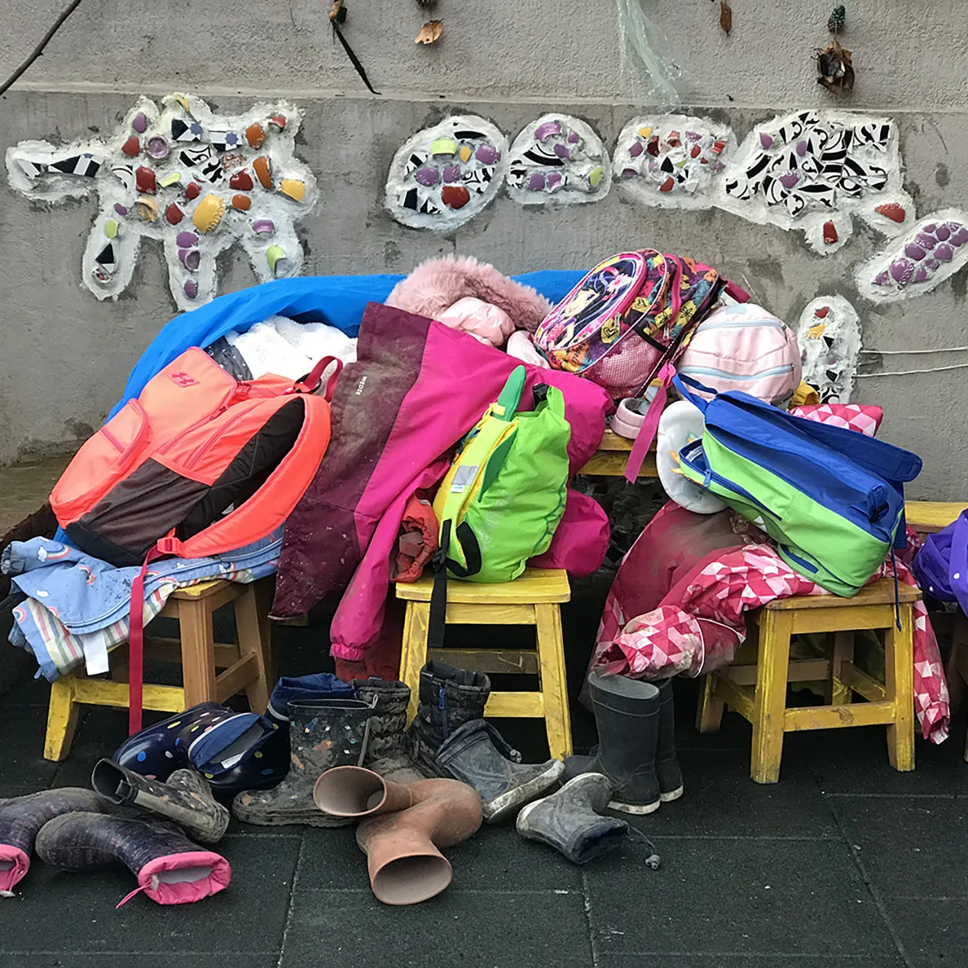 Ein Haufen Kinder-Regenkleidung, Taschen und Winterstiefel