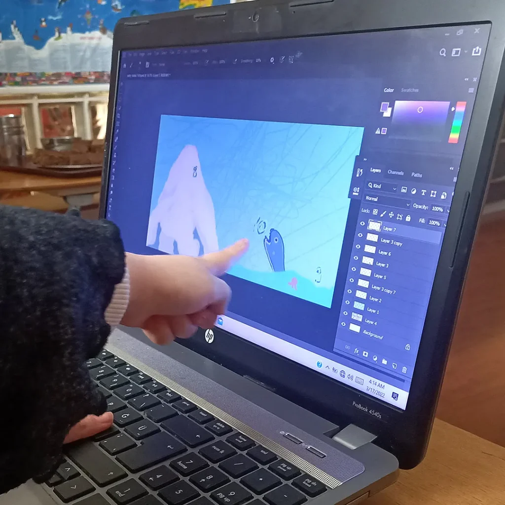 Ein Kind zeigt mit dem Finger auf den PC Bildschirm